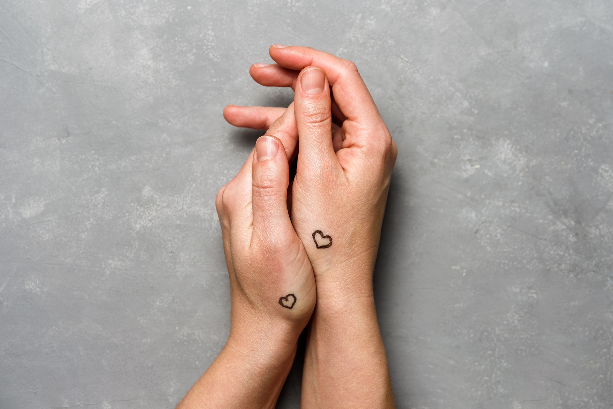 Hands with hearts tattoo on gray