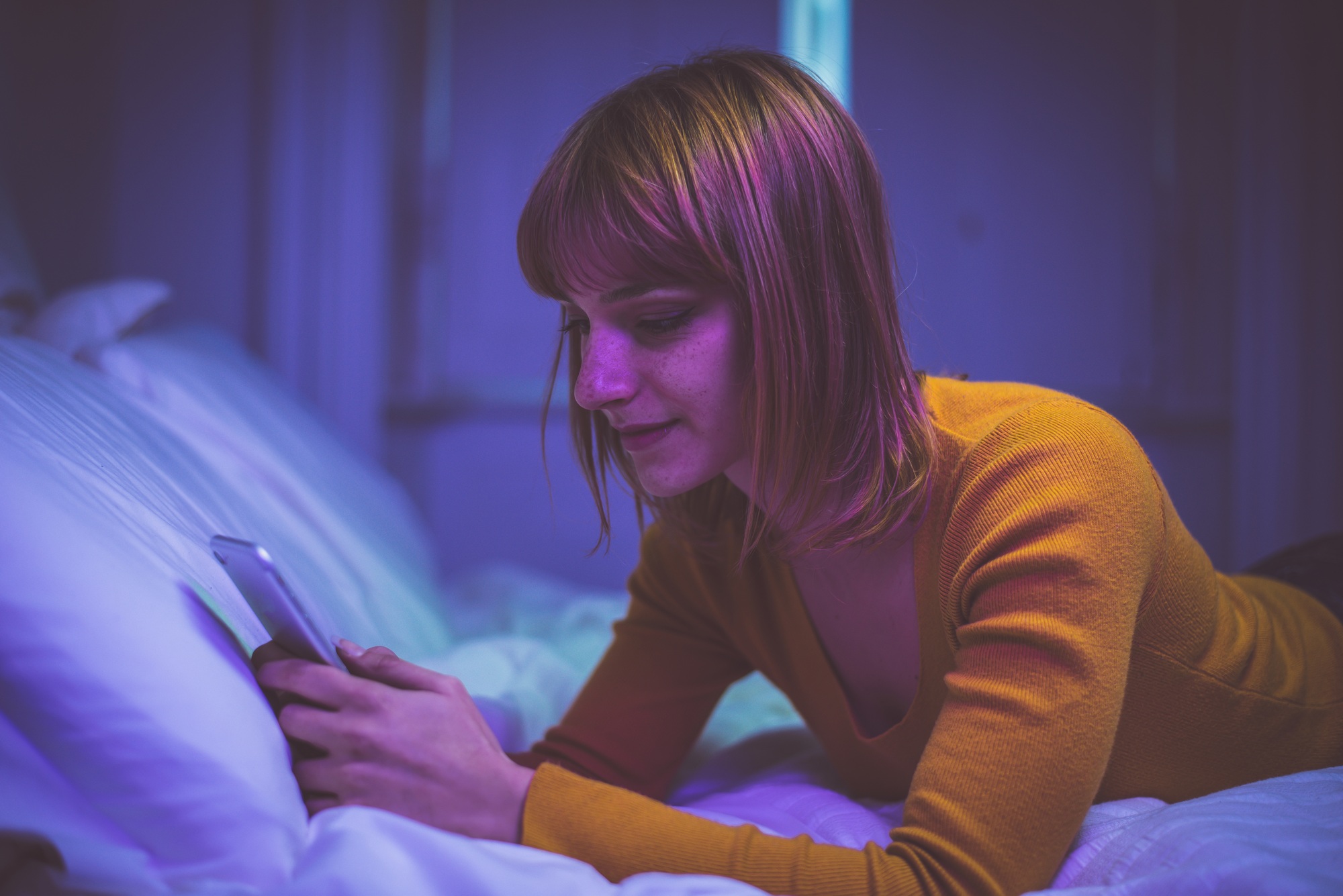 Young woman texting on the phone while lying in bed