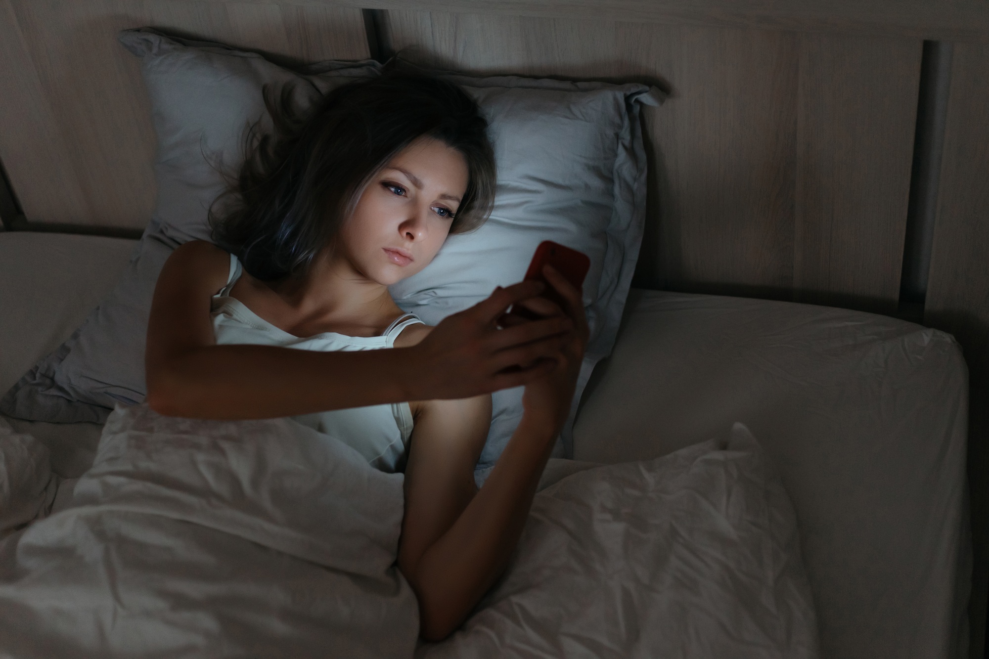 Female using smartphone in bed at night.
